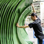 Ein Mann hebt eine große grüne Kunststoffform in einer industriellen Umgebung an.