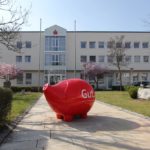 Rotes Sparschwein mit der Aufschrift 'Gut.' vor einem Sparkassengebäude.