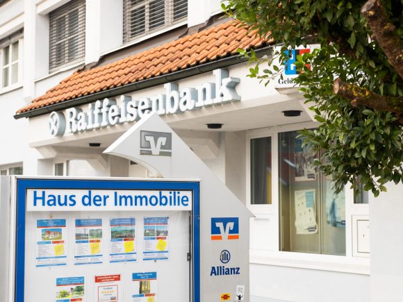Fassade der Raiffeisenbank mit Informationsschild über Immobilienangebote.