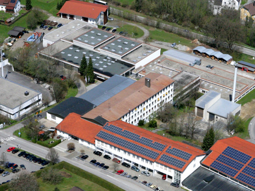 Luftaufnahme eines Industriegebiets mit mehreren Gebäuden und Solarpanelen auf den Dächern.