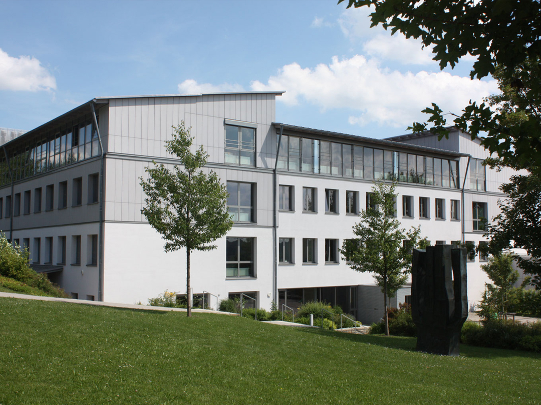 Moderne Schulgebäudeansicht des Gymnasiums Freyung mit Fenstern und Grünflächen.