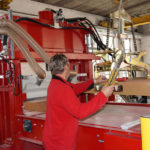 Ein Mitarbeiter bedient eine Holzverarbeitungsmaschine in einer Werkstatt.