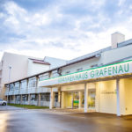 Eingang des Krankenhauses Grafenau mit einem modernen Gebäude und einem überdachten Eingangsbereich.