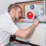 Techniker arbeitet an der Wartung eines Geräts mit einem Werkzeug in der Hand.