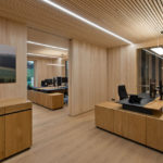 Ein modernes Büro mit Holzverkleidung und Schreibtischen aus Holz und Schwarz.