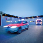 Ein Rettungswagen des Bayerischen Roten Kreuzes fährt aus einer modernen Rettungsstation.