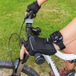 Person hält den Lenker eines Mountainbikes mit Handschuhen und trägt eine Smartwatch am Handgelenk.