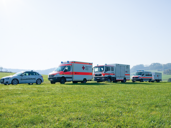 Drei Rettungsfahrzeuge und ein Einsatzfahrzeug auf einem Feld in ländlicher Umgebung.