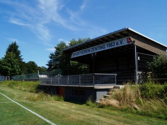 Blick auf die Tribüne des Sportvereins Zenting 1963 e.V. mit einem klaren Himmel im Hintergrund.