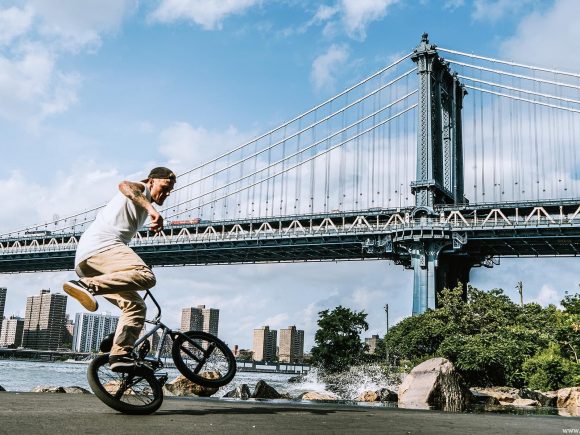 Ein Fahrradfahrer, der Tricks auf einem BMX-Fahrrad vor der Manhattan-Brücke in New York City ausführt.