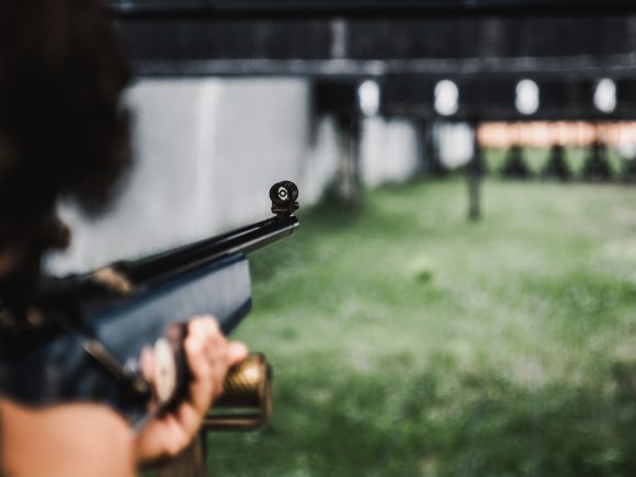 Nahaufnahme einer Person, die mit einem Gewehr auf ein Ziel schießt.