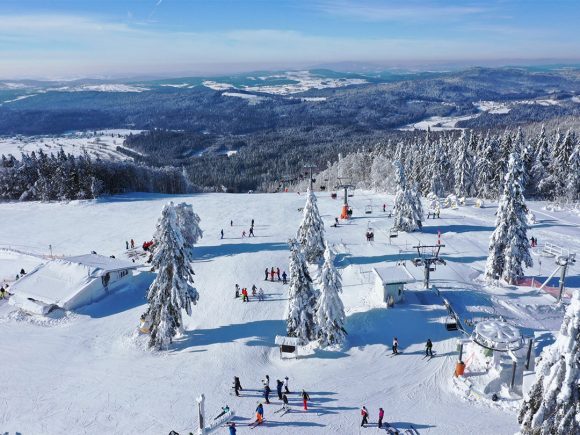 Schneebedeckte Landschaft im Skizentrum Mitterdorf mit Skifahrern und Sesselliften.