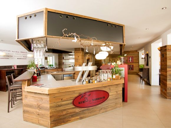 Holztheke mit Barhockern in einem modernen Restaurant mit minimalistischer Einrichtung.