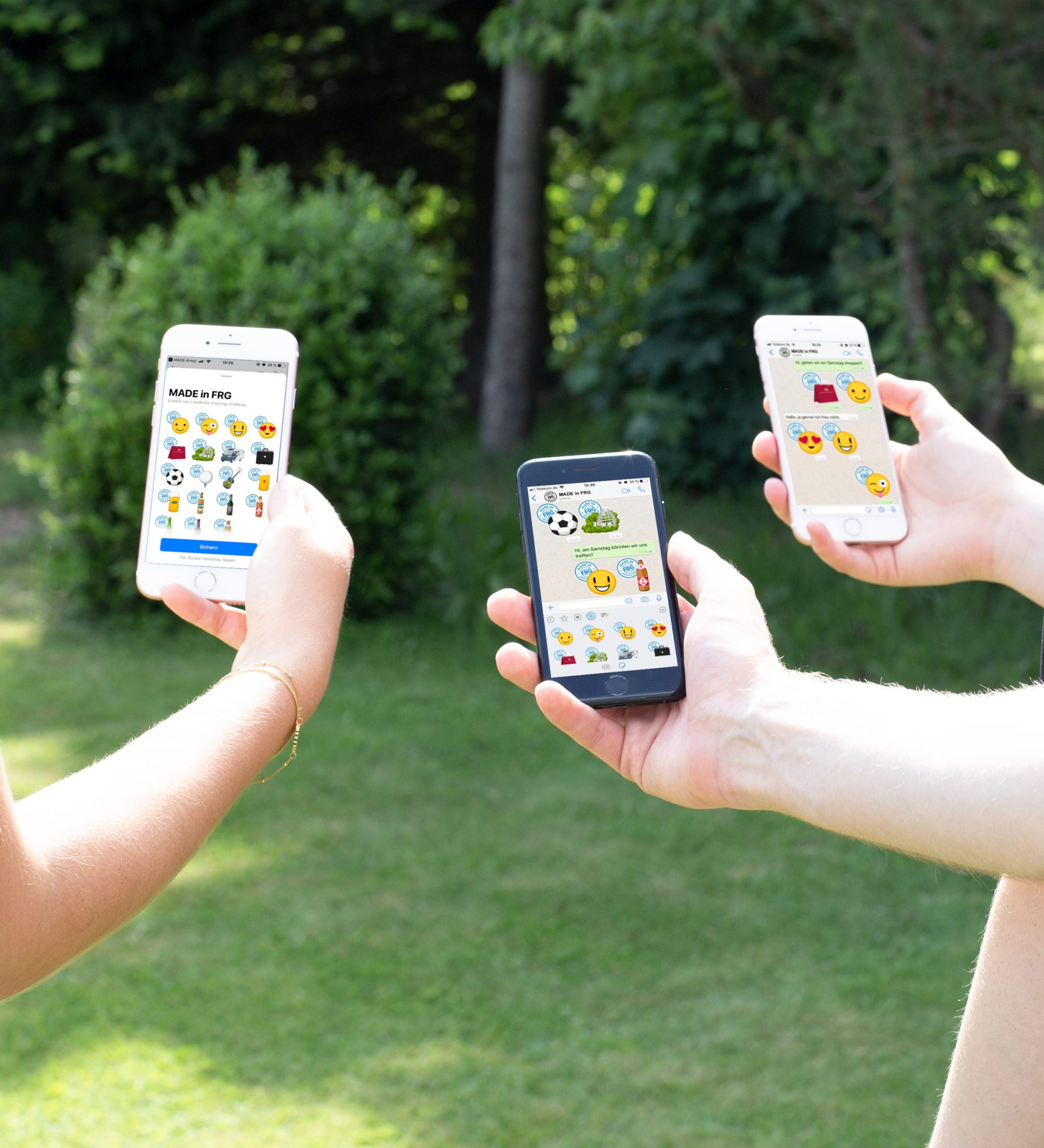 Drei Personen halten Smartphones mit Emoji-Anwendungen in der Hand, die verschiedene Emojis anzeigen.