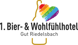 Das farbige Herz-Logo mit Regenbogenstreifen zeigt den Schriftzug 1. Bier- & Wohlfühlhotel Gut Riedelsbach in dunklem Grau auf hellem Grund.