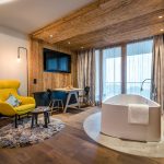 Ein modernes Zimmer mit freistehender Badewanne, Holzdecke und einem Tisch mit Stühlen.