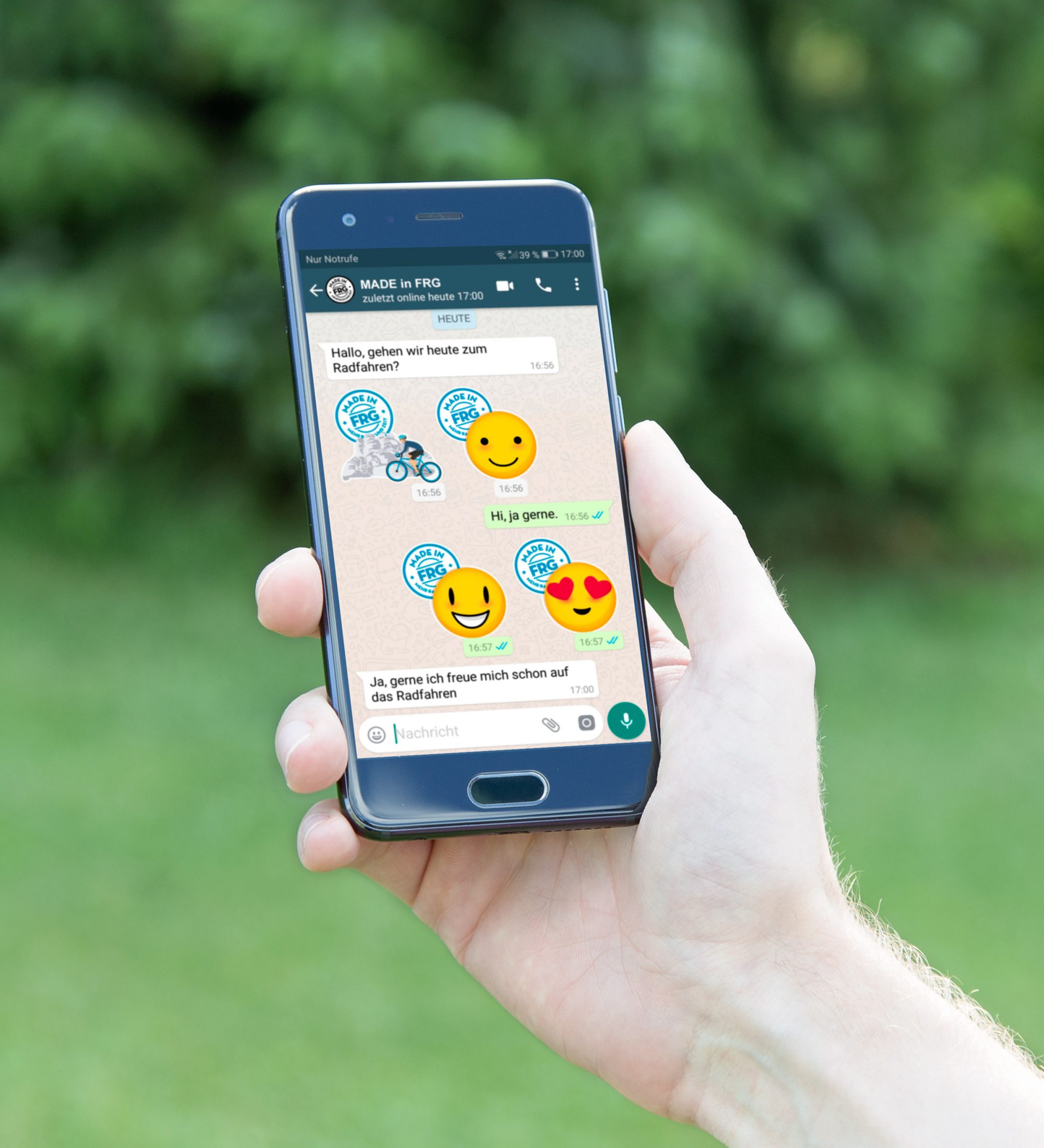 Ein Smartphone in der Hand zeigt WhatsApp-Nachrichten mit Emojis und Texten auf dem Bildschirm.