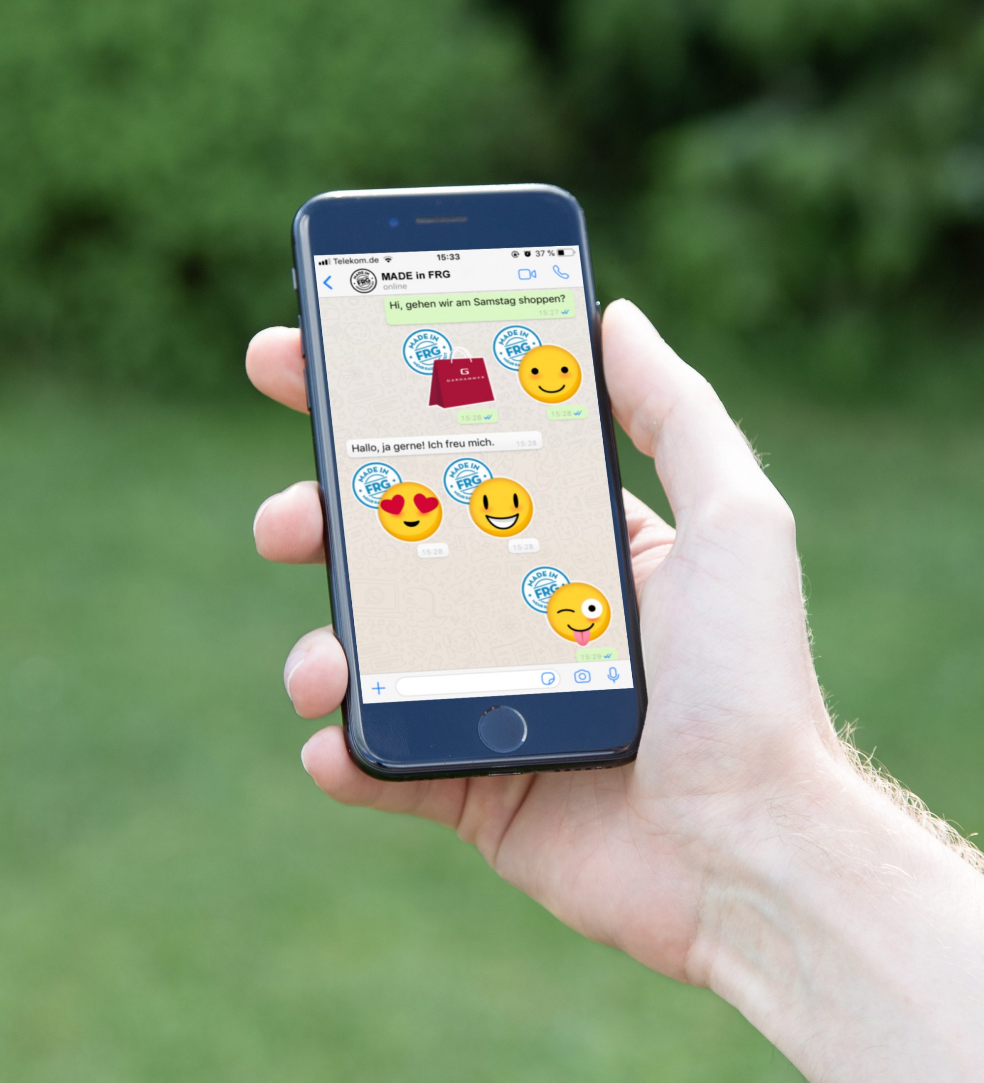 Ein Smartphone in einer Hand zeigt WhatsApp-Nachrichten mit Emojis auf dem Bildschirm.