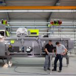 Zwei Techniker überprüfen eine große Maschine in einer Industriehalle.