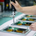 Eine Hand, die einen Schraubendreher verwendet, um elektronische Bauteile zusammenzusetzen.
