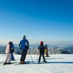 Gruppe von Skifahrern in Winterkleidung auf einem schneebedeckten Hang.