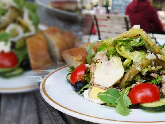 Ein Teller mit Thunfischsalat, gemischtem Gemüse und frischem Brot auf einem Tisch.