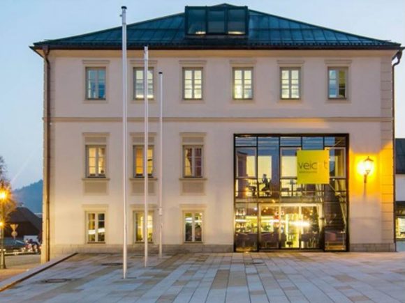 Gebäude mit großen Fenstern und gelbem Schild, das den Namen 'veic' zeigt.
