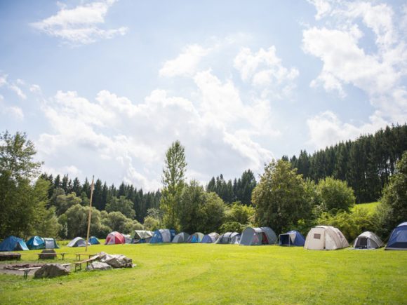 Eine Reihe von Zelten auf einer Wiese unter einem blauen Himmel mit Wolken.
