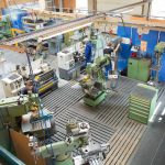 Blick auf eine Werkstatt mit verschiedenen Maschinen und mehreren Mitarbeitern bei der Arbeit.