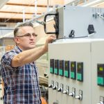 Mitarbeiter überprüft eine Steuerungseinheit in einer industriellen Umgebung.