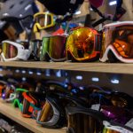 Verschiedene Skibrillen mit reflektierenden Gläsern auf einem Regal in einem Geschäft.