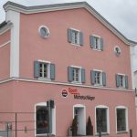 Fassade eines rosa Gebäudes mit Fenstern und dem Schriftzug 'Sport Michetschläger'.