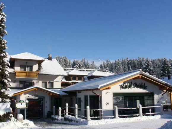 Das Gebäude der Kleblmühle im Winter, umgeben von Schnee und Bäumen.