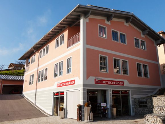 Zweistöckiges Gebäude mit rosaner Fassade und Geschäftsschild 'Michetschlager'.