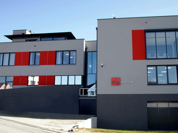 Modernes Bürogebäude mit großen Fenstern und roten Akzenten an der Fassade.
