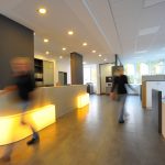 Moderne Empfangshalle mit beleuchtetem Empfangstresen und Personen im Hintergrund.