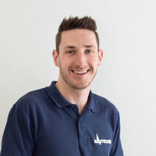 Porträt eines Mannes mit kurzem Haar, der in einem blauen Poloshirt lächelt.