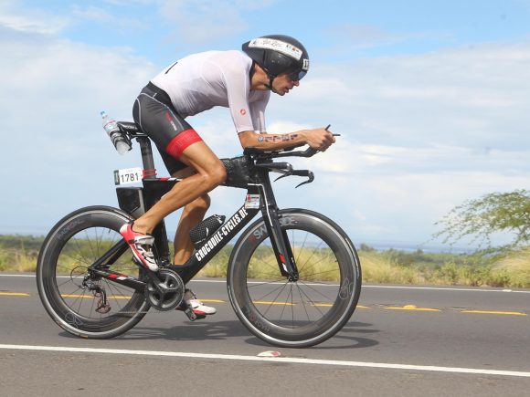 Ein Radfahrer in Wettkampfkleidung fährt auf einem Triathlon-Bike während eines Rennens.