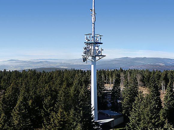 Haidel Sendeturm mit Antennen auf einem hohen Mast in einem Waldgebiet.