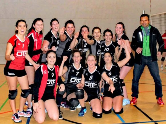 Volleyballteam bestehend aus mehreren Spielerinnen in Sportkleidung, lächelnd und posierend für das Foto.