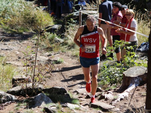 Ein Läufer in Sportkleidung mit der Nummer 253 während eines Wettkampfs im Wald.