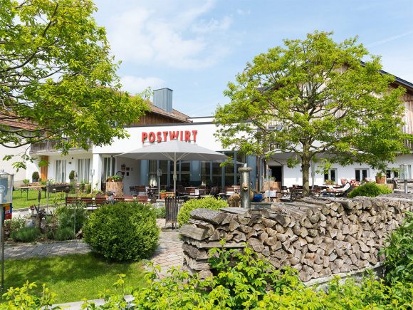 Das Gebäude des Restaurants Postwirt mit einem großen Schild und Außenbereich.
