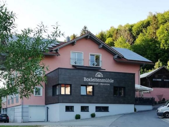 Fassade des Gasthofs Boxleitenmühle mit einem modernen Anbau und einem traditionellen Obergeschoss.