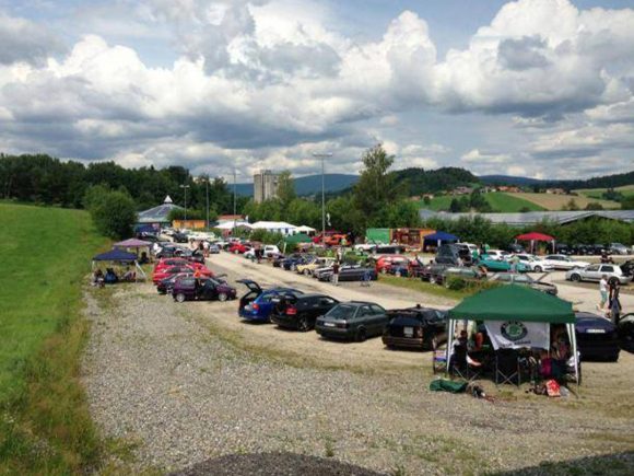 Motorradtreffen mit verschiedenen Fahrzeugen und Zelten auf einem Parkplatz.