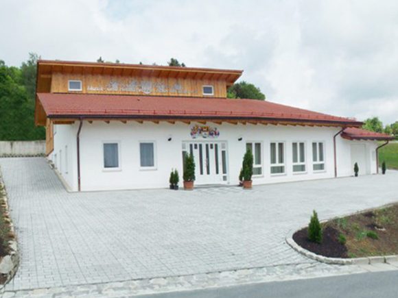 Weißes Gebäude mit rotem Dach und großen Fenstern, das den Musik- und Heimatverein beherbergt.