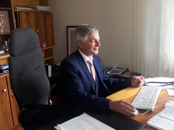 Ein Mann in einem Anzug sitzt an einem Schreibtisch und arbeitet am Computer.