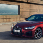 Roter BMW 4er Gran Coupe steht auf einer gepflasterten Fläche mit einer Stadt im Hintergrund.