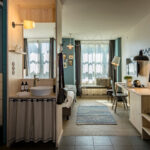 Doppelzimmer mit einem Badezimmerbereich, einem Schreibtisch und einem Bett in einem modernen Stil.