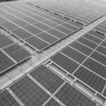 Dachansicht einer Photovoltaikanlage mit mehreren Solarpanelen in Schwarz-Weiß.