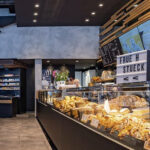 Verkaufsbereich einer Bäckerei mit einer Vitrine voller frischer Backwaren und einem modernen Interieur.